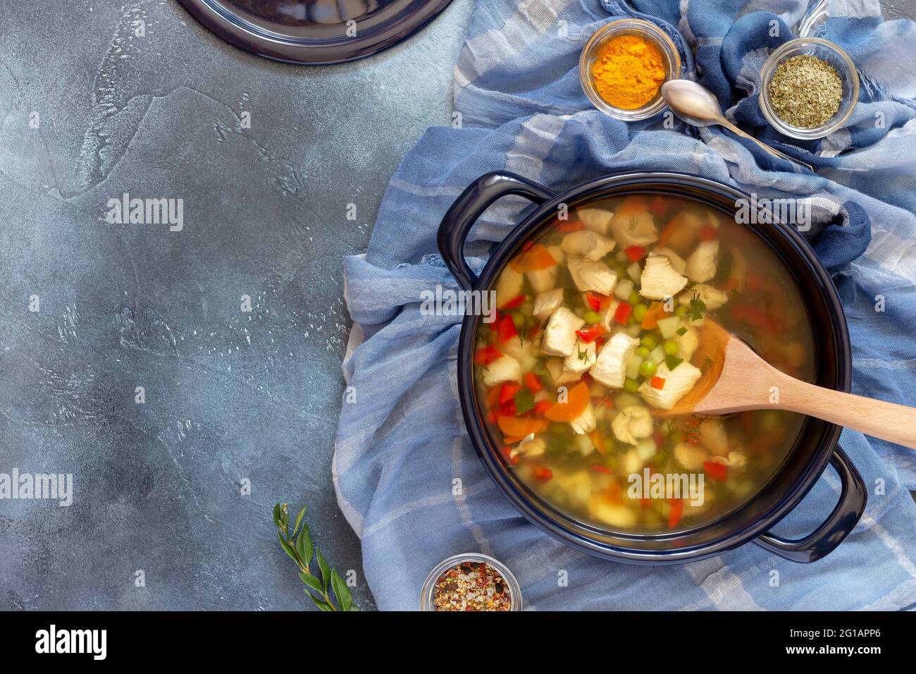 Composizione alimentare orizzontale con pentola grande con zuppa di pollo ebrea calda e spezie su sfondo blu con spazio per la copia. Cibo sano e gustoso Foto Stock