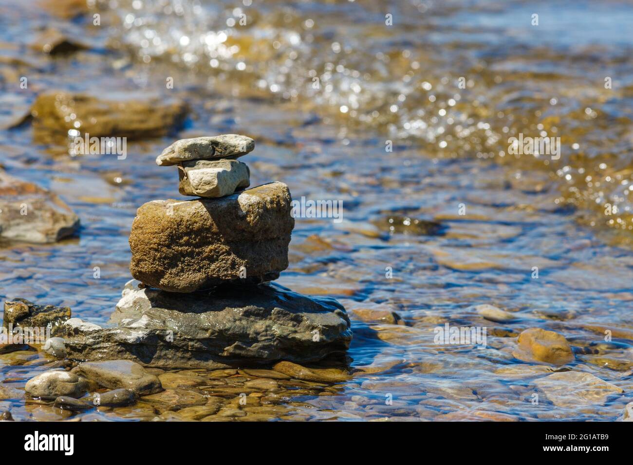 Le pietre sono equilibrate e accatastate l'una sull'altra nelle acque poco profonde di una spiaggia rocciosa al bordo di un fiume. Foto Stock