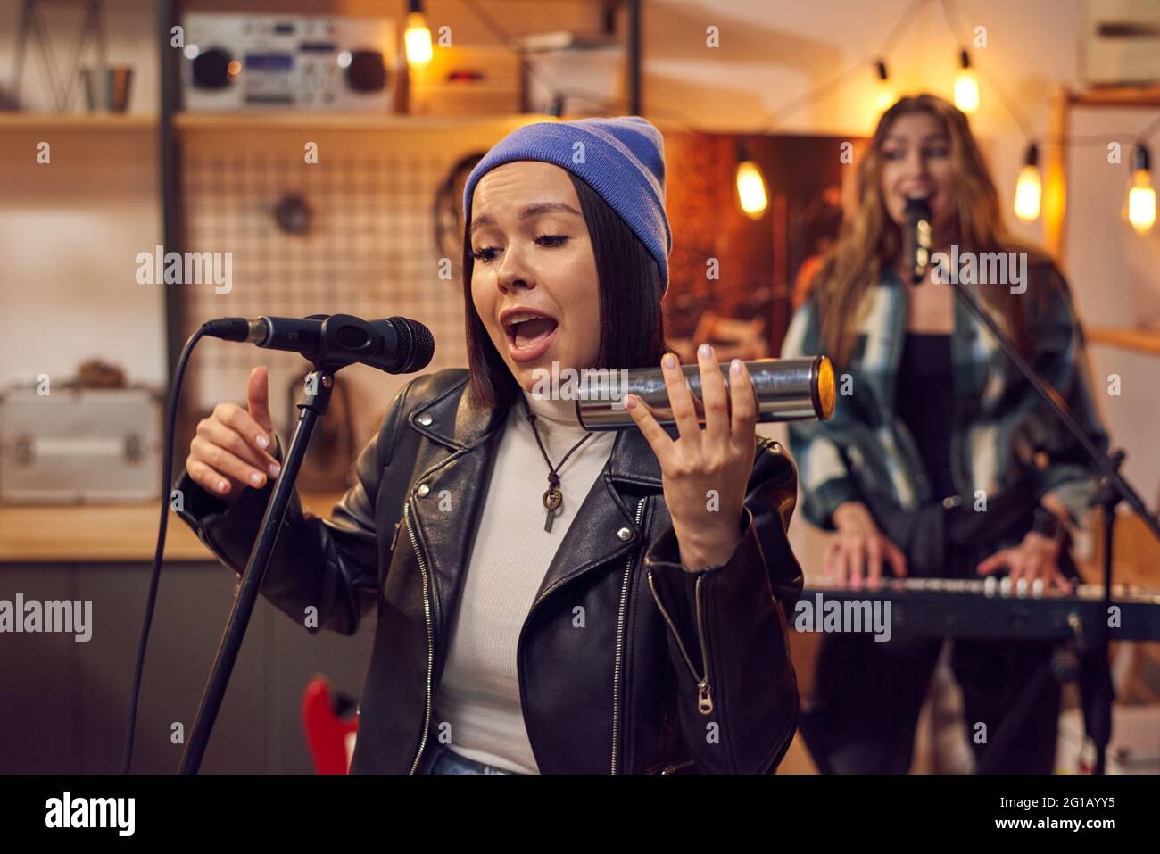 Giovane donna che canta e suona strumento musicale in studio Foto Stock