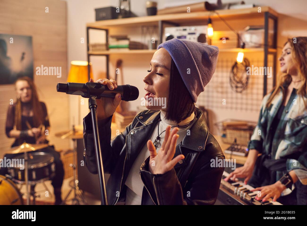 Giovane graziosa musicista femminile che registra canzoni con band in studio Foto Stock
