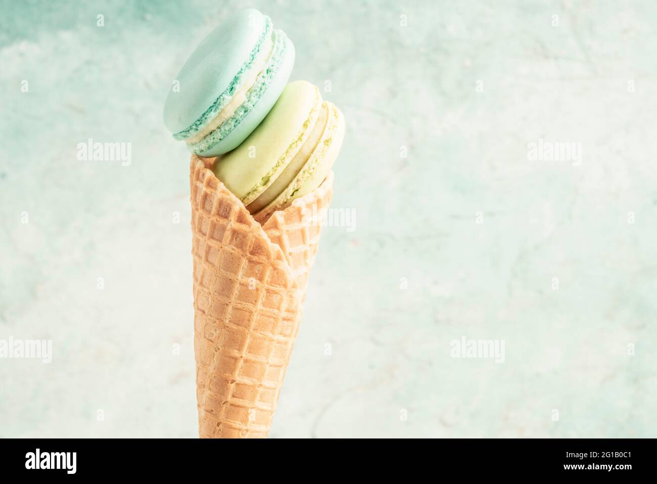 macaroon in un cono gelato waffle su sfondo verde con spazio per la copia Foto Stock
