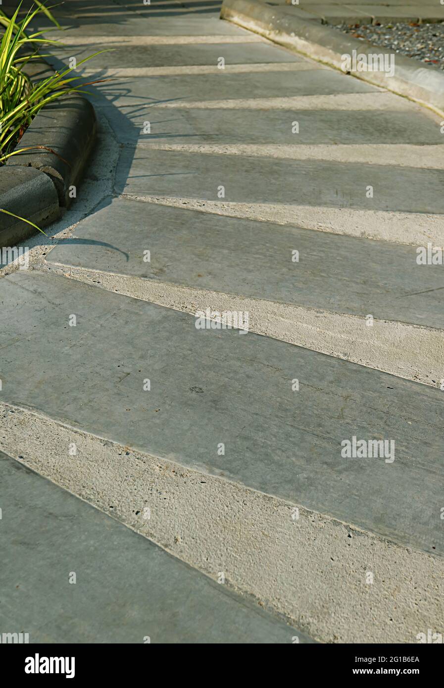 Percorso vuoto curvo a strisce in cemento alla luce del sole Foto Stock