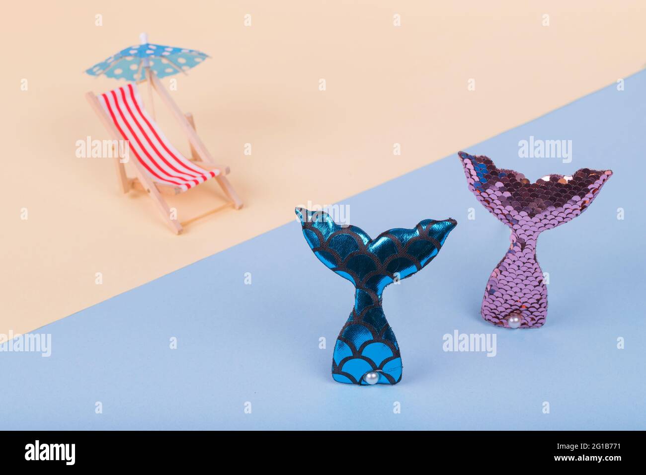 Il concetto minimo è costituito da sdraio e ombrellone su una spiaggia e da una coda di sirena che esce dall'acqua. Concetto creativo di vacanza estiva. Co Foto Stock