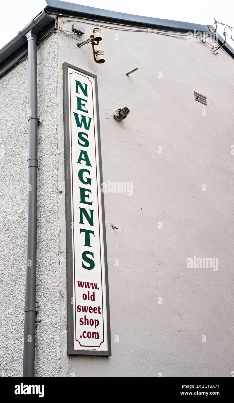 Lungo e stretto cartello 'Newsagents' sulla parete esterna dell'edificio Foto Stock