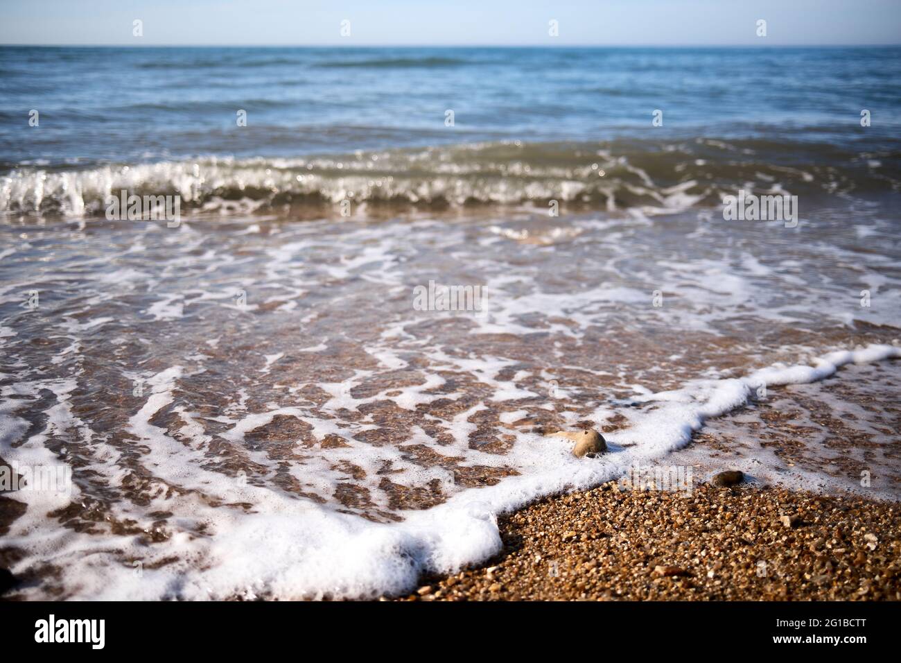 Piccole onde si rompono su una spiaggia di piccoli ciottoli a Charmouth in Dorset Foto Stock