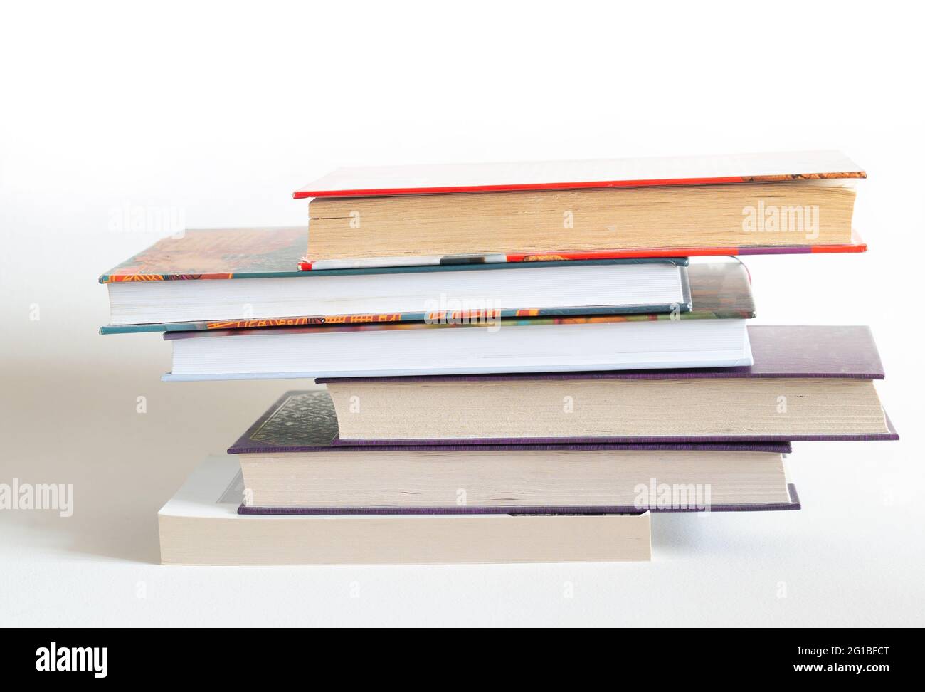 Pila di libri di copertina rigida su sfondo bianco Foto Stock