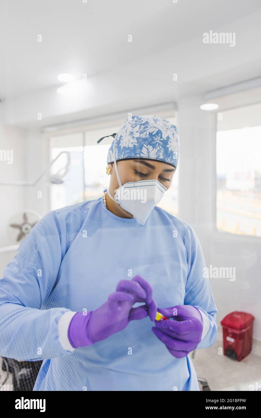 Medico femminile adulto in uniforme e maschera respiratoria apertura tubo in ospedale con lampade lucide Foto Stock