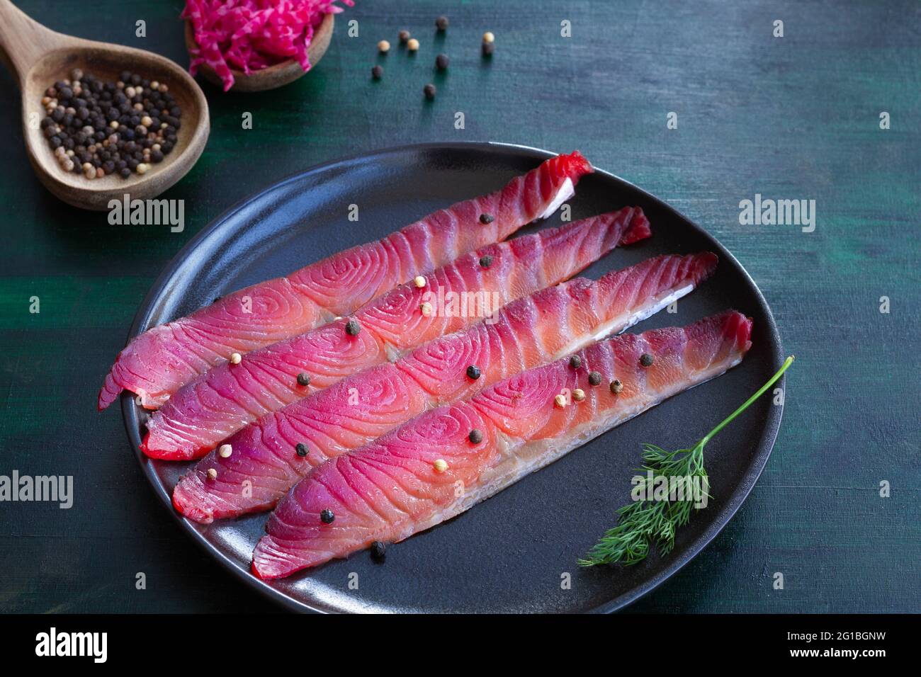 Da sopra gravlax con peppercorne miste e sprigg di aneto fresco su piatto su fondo scuro Foto Stock