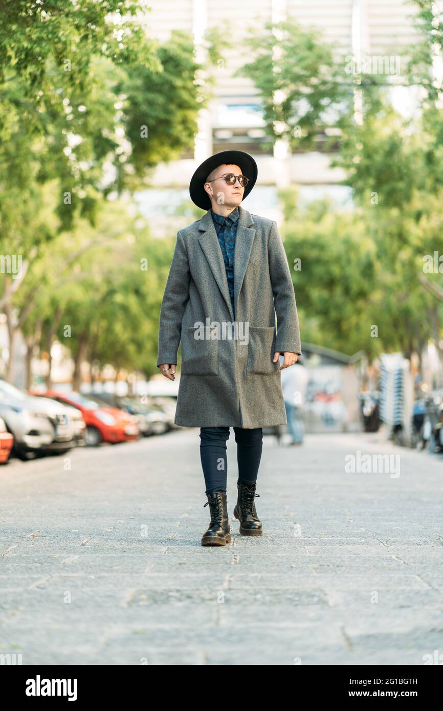 Giovane uomo transgender in cappotto e cappello di classe che guarda via  alla luce del giorno Foto stock - Alamy