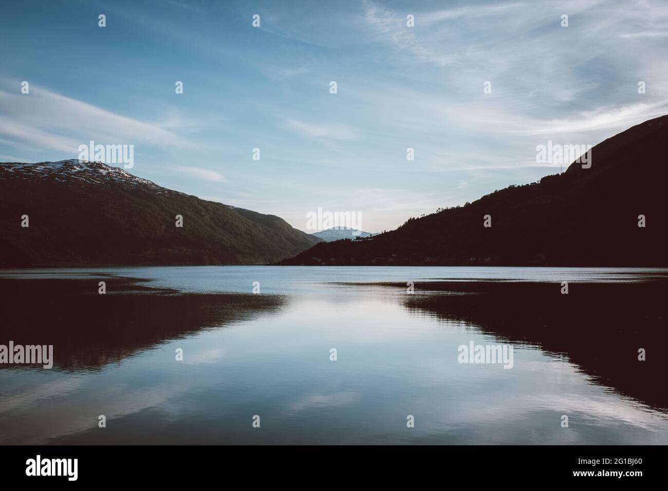 Paesaggio scenico con ruscello d'acqua che scorre tra le colline ricoperte di piante in cupa giornata di sole Foto Stock