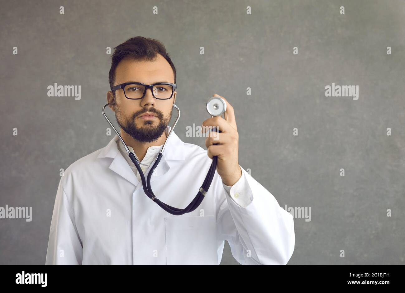 Ritratto di un giovane medico che tiene uno stetoscopio e guarda la fotocamera Foto Stock