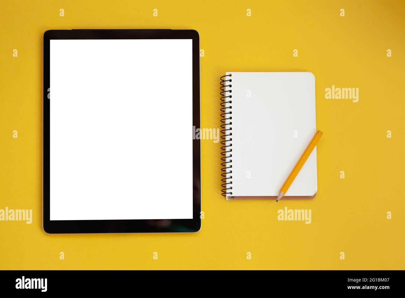 Mockup dello schermo del tablet e blocco note isolato su sfondo giallo, vista dall'alto Foto Stock