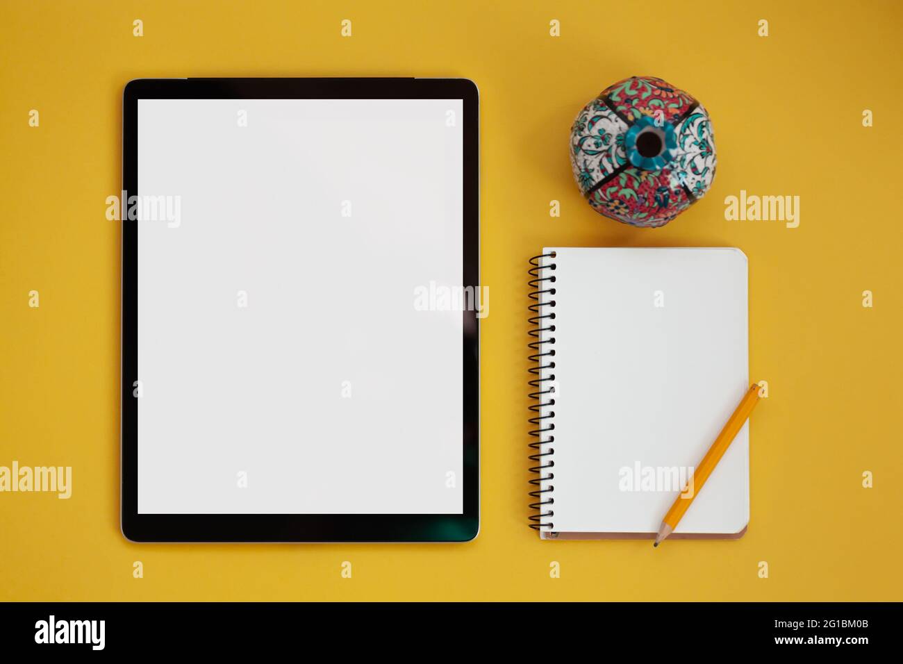 Mockup dello schermo del tablet e blocco note isolato su sfondo giallo, vista dall'alto Foto Stock