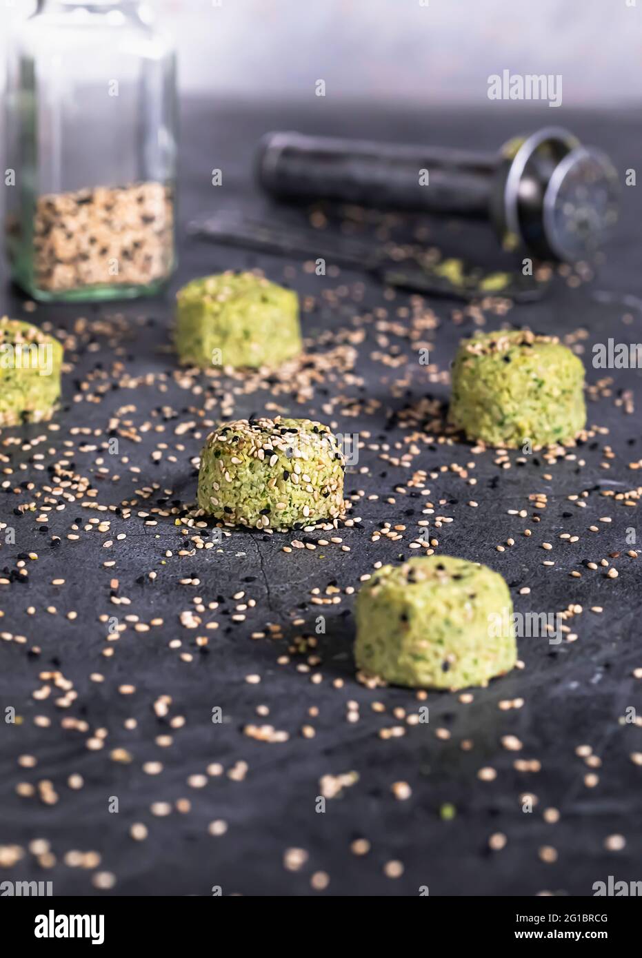 Immagine con falafel grezzo che gocciola con sesamo. Una paletta di falafel sullo sfondo. Foto Stock