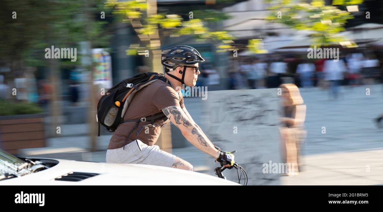 Belgrado, Serbia - 5 giugno 2021: Giovane uomo tatuato che cavalca una bicicletta sul traffico cittadino in una giornata di sole Foto Stock