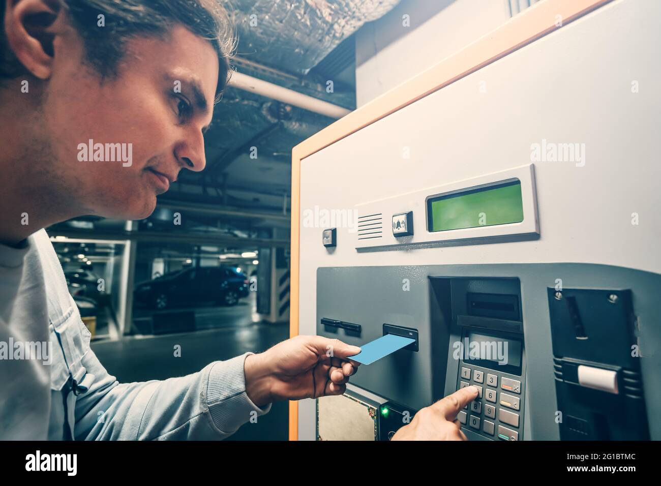L'uomo paga per il parcheggio in una macchina speciale con carta di credito. Foto Stock