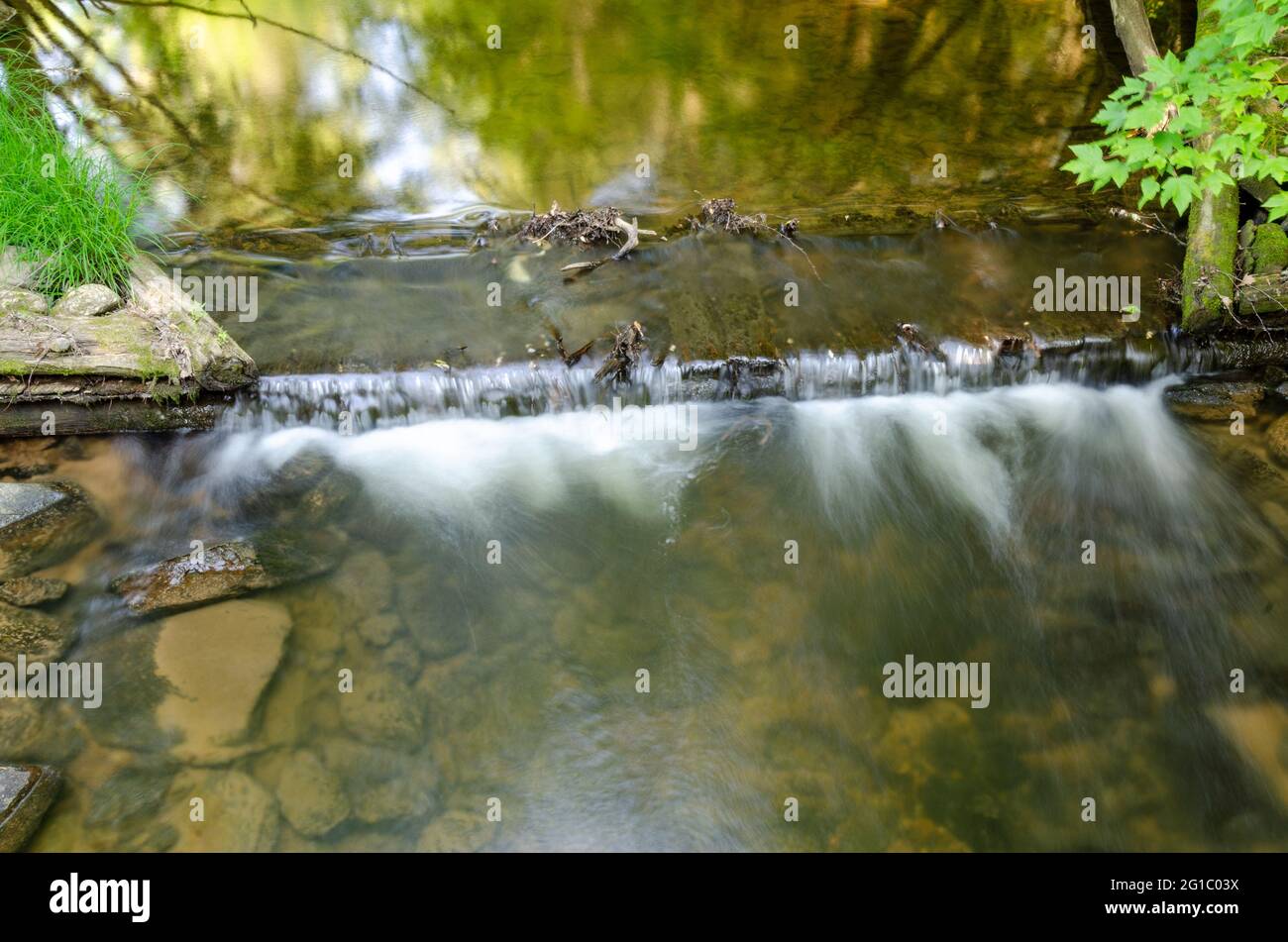 Lunga esposizione di acqua che cade su una stramazzo in un torrente Foto Stock