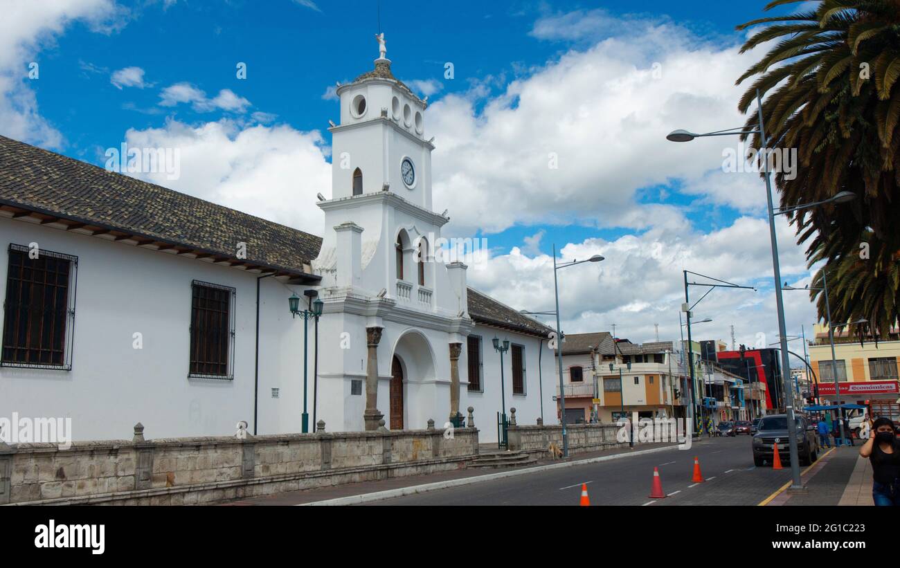Salcedo, Cotopaxi / Ecuador - 5 giugno 2021: Persone che camminano di fronte alla chiesa di San Miguel de Salcedo nel centro della città in una giornata di sole Foto Stock