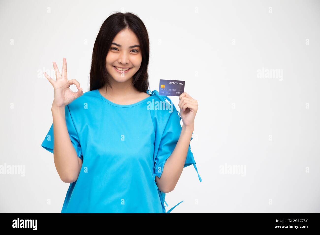 Giovane asiatico bella donna paziente mostrando carta di credito assicurazione infortuni personale e ok segno isolato su sfondo bianco, PA e reclamo di salute serv Foto Stock