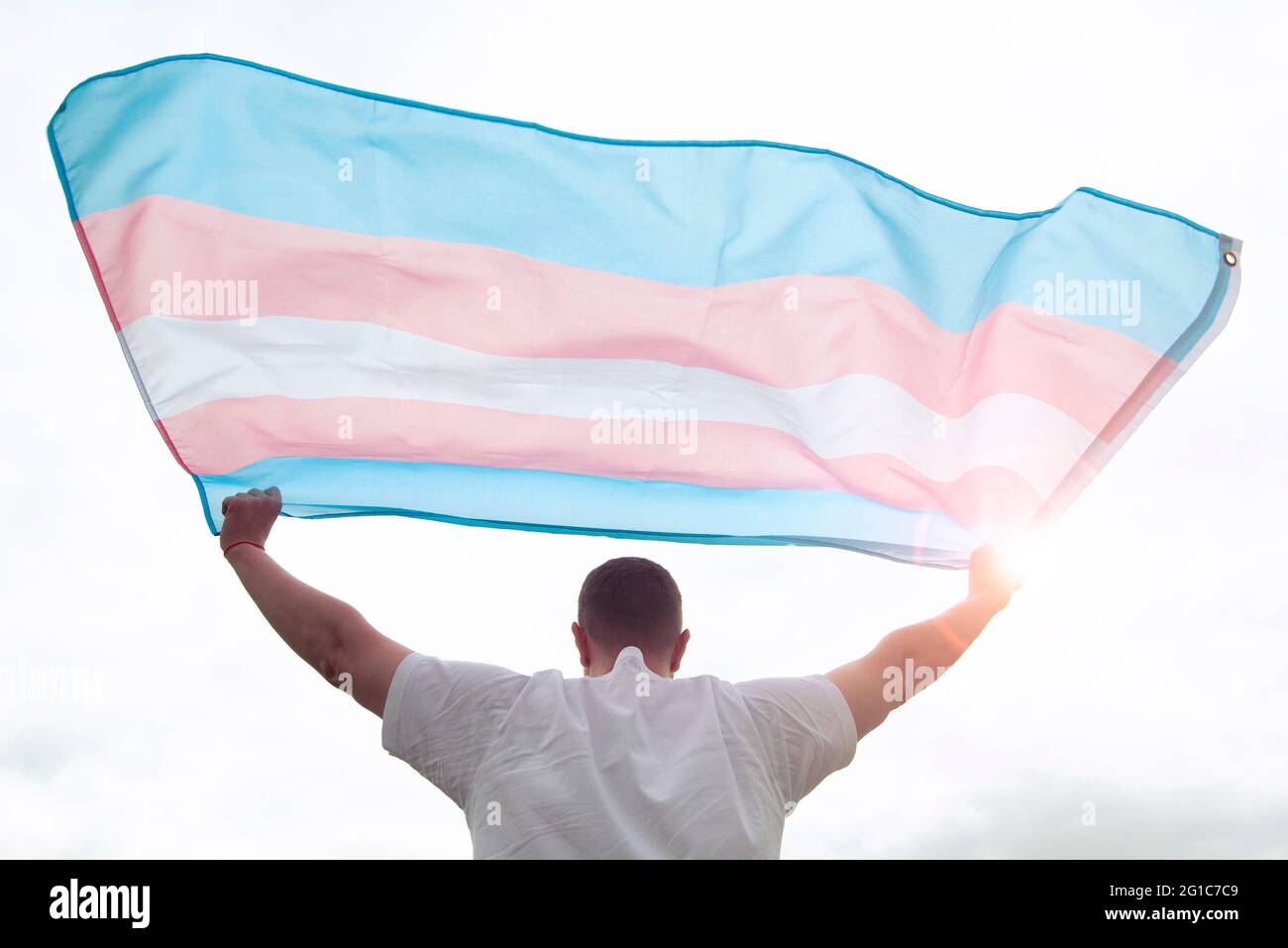 Uomo transgender che tiene sventolando bandiera transgender, immagine concettuale sui diritti umani, uguaglianza nel mondo Foto Stock