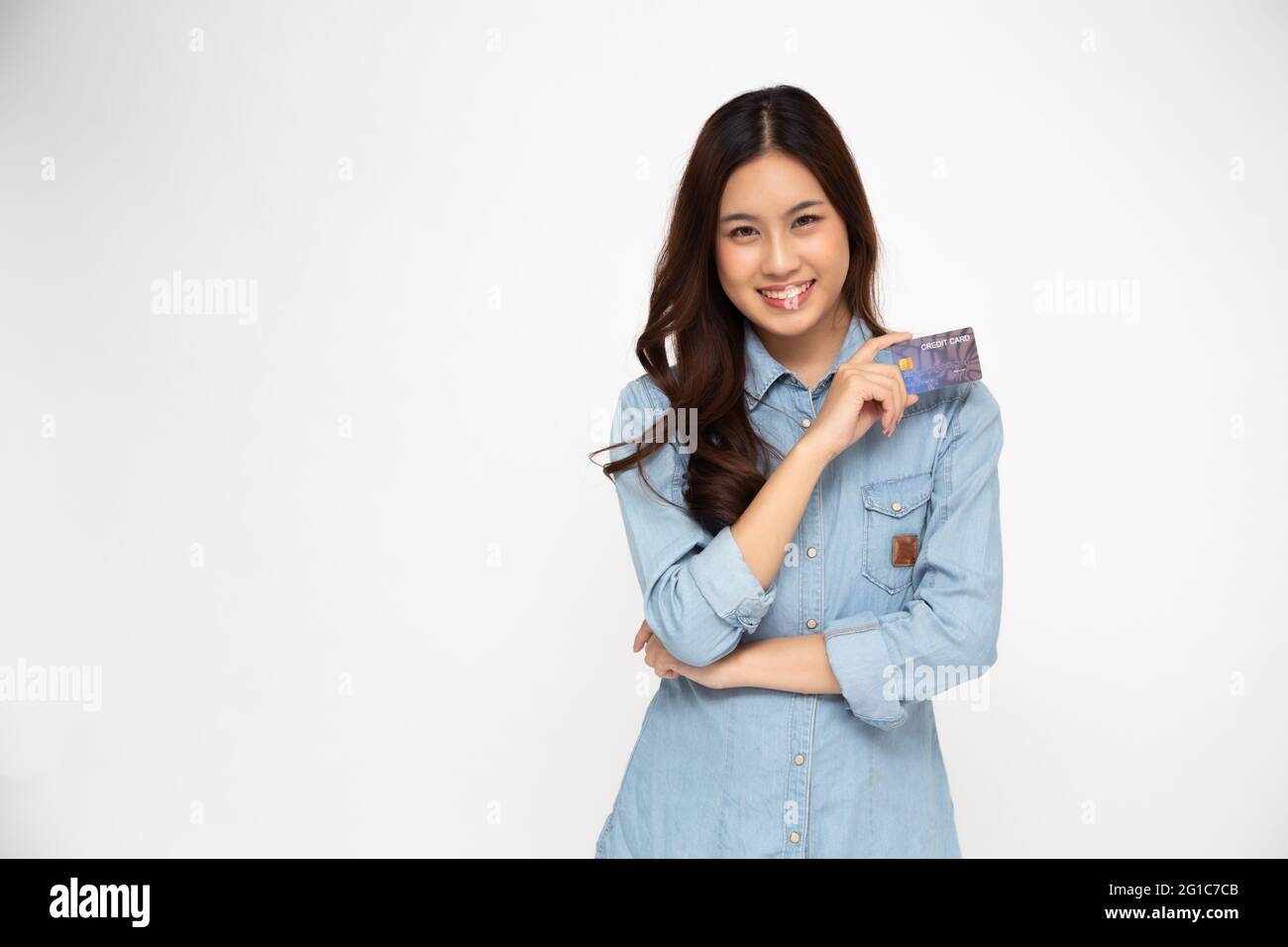 Ritratto di donne asiatiche che indossano una camicia blu jean con carta di credito e sorriso isolato su sfondo bianco, giovane donna sorridente e guardando camer Foto Stock