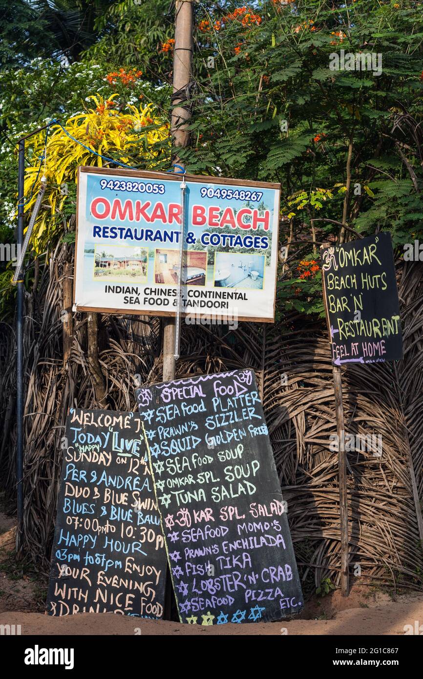 Cartello stradale per Omkar Beach Restaurant & Cottages con menu scritto a mano della tavola dei loro ristoranti, Agonda, Goa, India Foto Stock