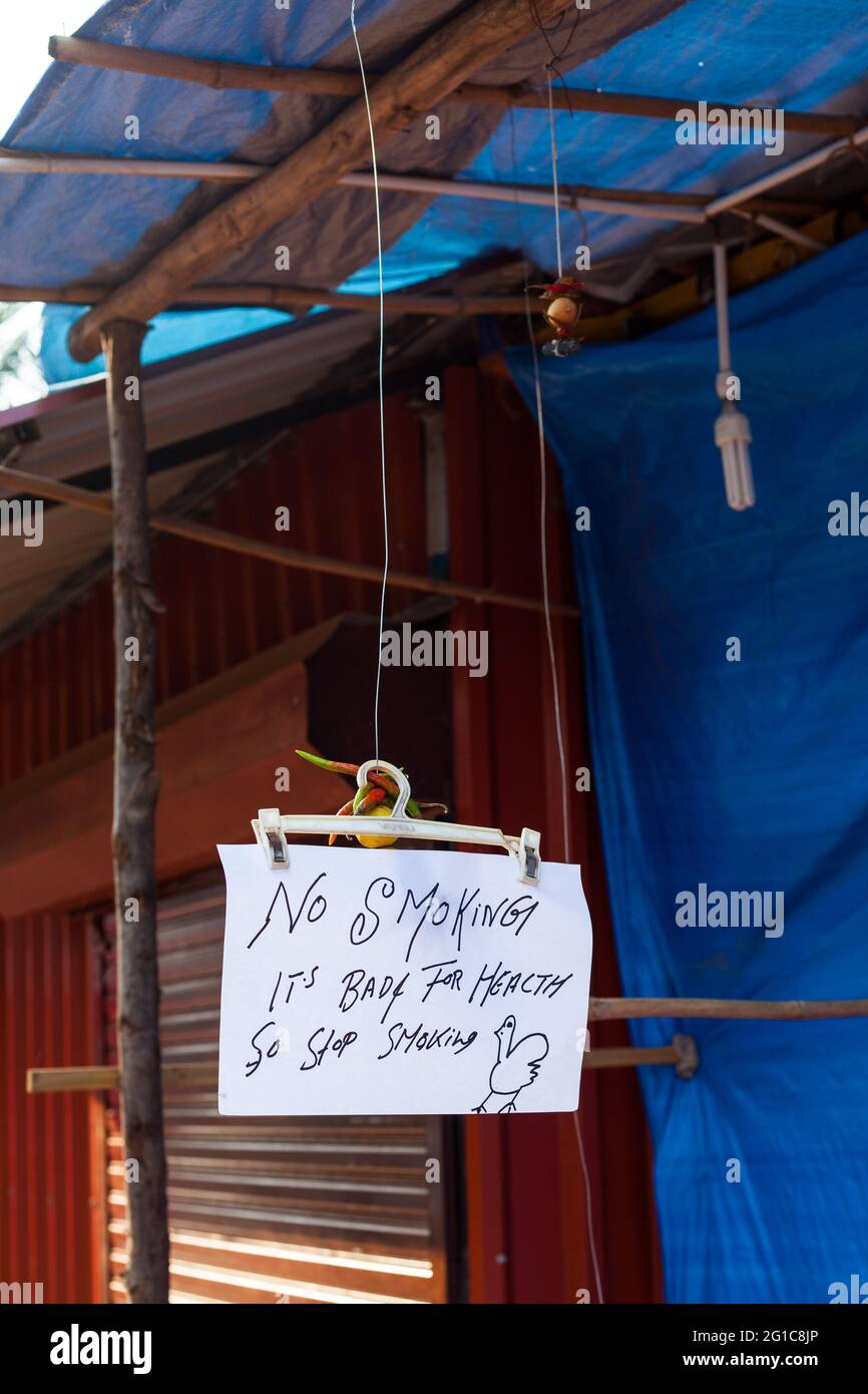 Avviso pubblico scritto a mano appeso a shack per 'No Smoking', con un disegno di un pollo, Agonda, Goa, India Foto Stock