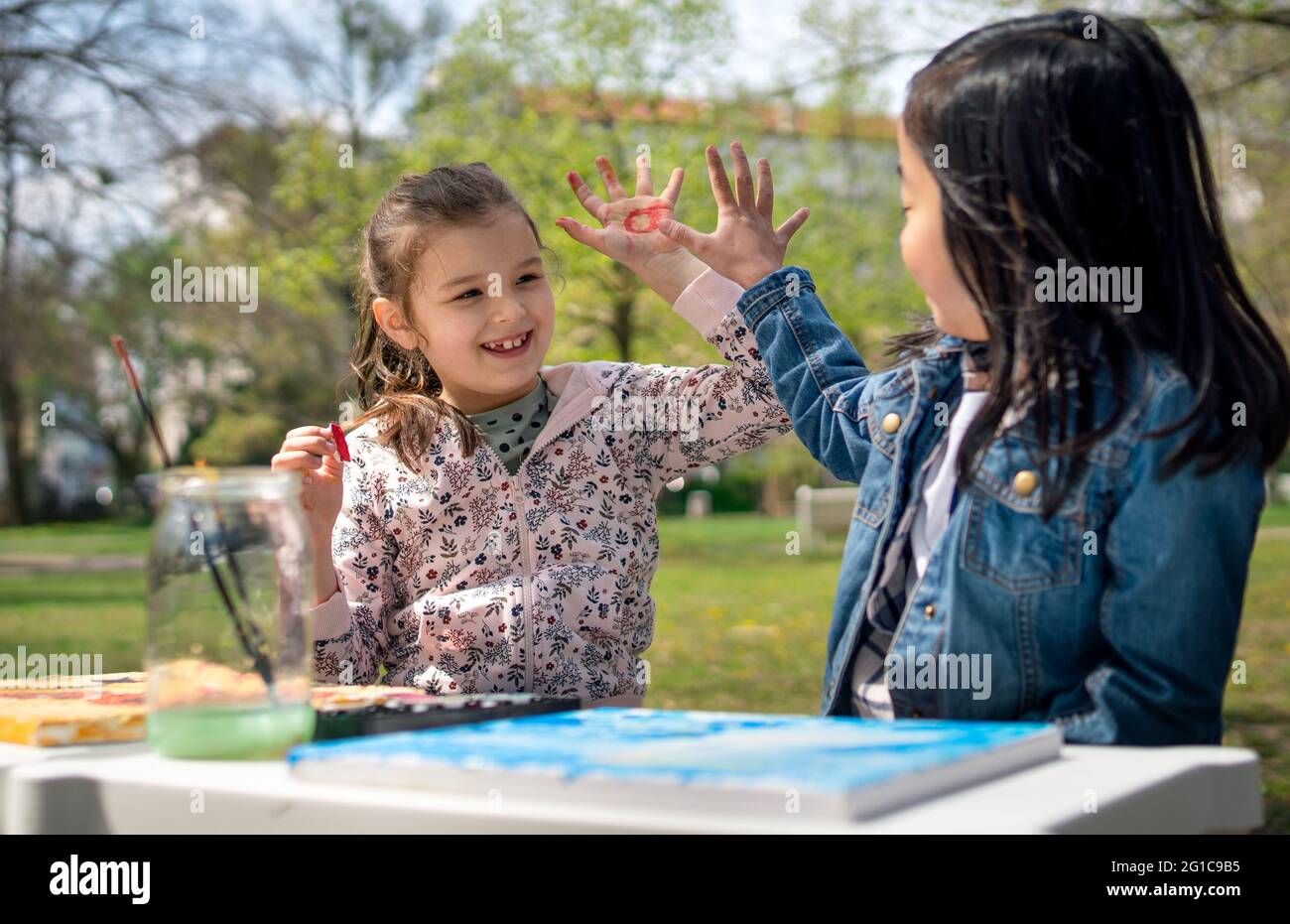Bambini piccoli dipingendo immagini all'aperto nel parco cittadino, imparando concetto di educazione di gruppo. Foto Stock