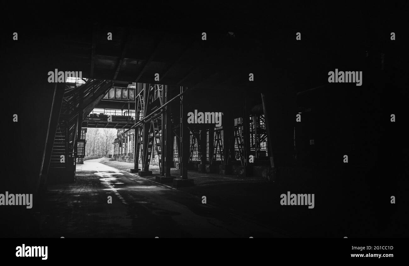 Piattaforma da un tunnel orribile a Zeche Zollverein nel parco paesaggistico Duisburg Nord in uno stile cupo e sbiadito. Giù il buco di coniglio Foto Stock