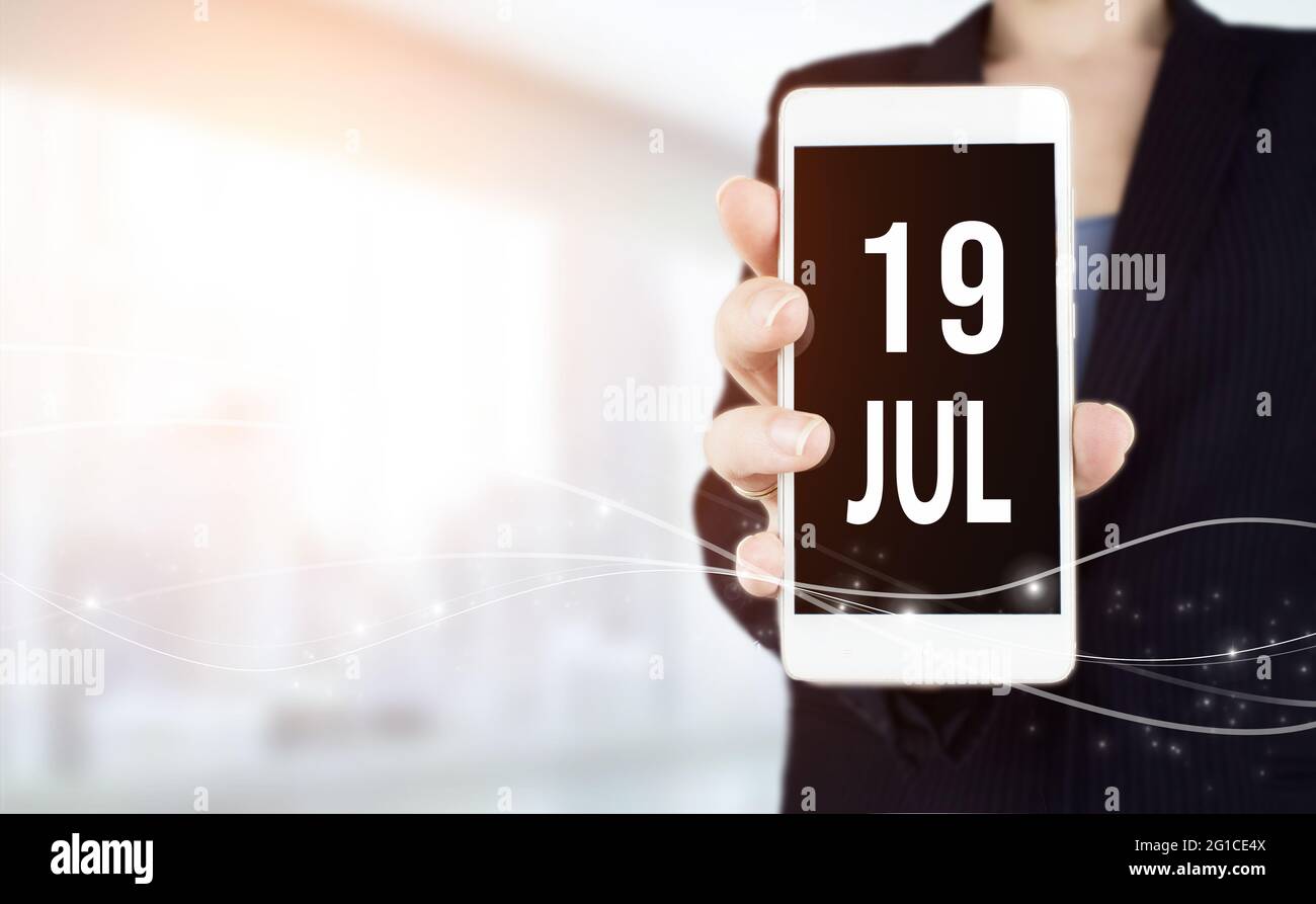 19 luglio. Giorno 19 del mese, data del calendario. Smartphone bianco con data calendario in mano di uomo d'affari su sfondo sfocato. Mese d'estate, giorno della y Foto Stock