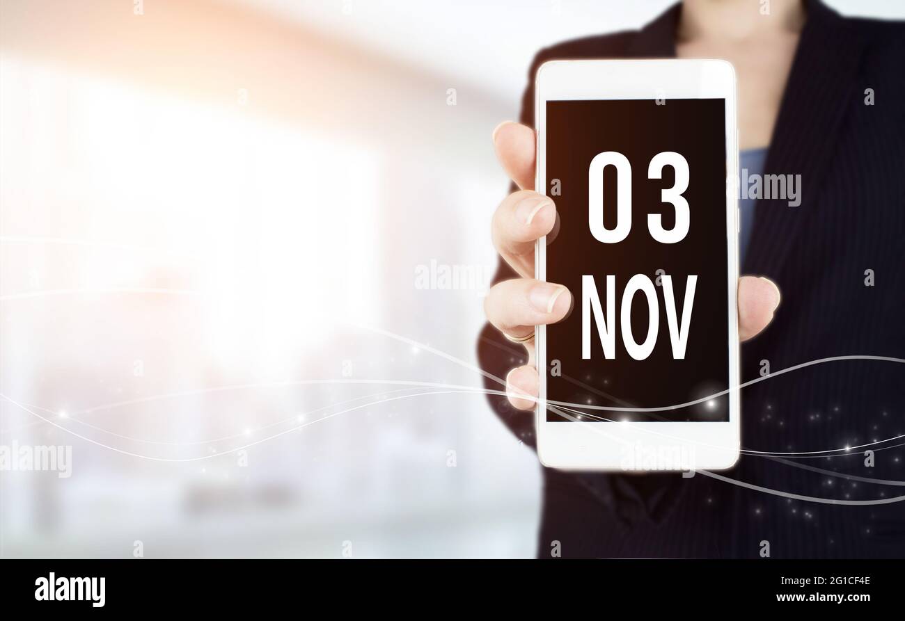 3 novembre. Giorno 3 del mese, data del calendario. Smartphone bianco con data calendario in mano di uomo d'affari su sfondo sfocato. Mese di autunno, giorno del Foto Stock