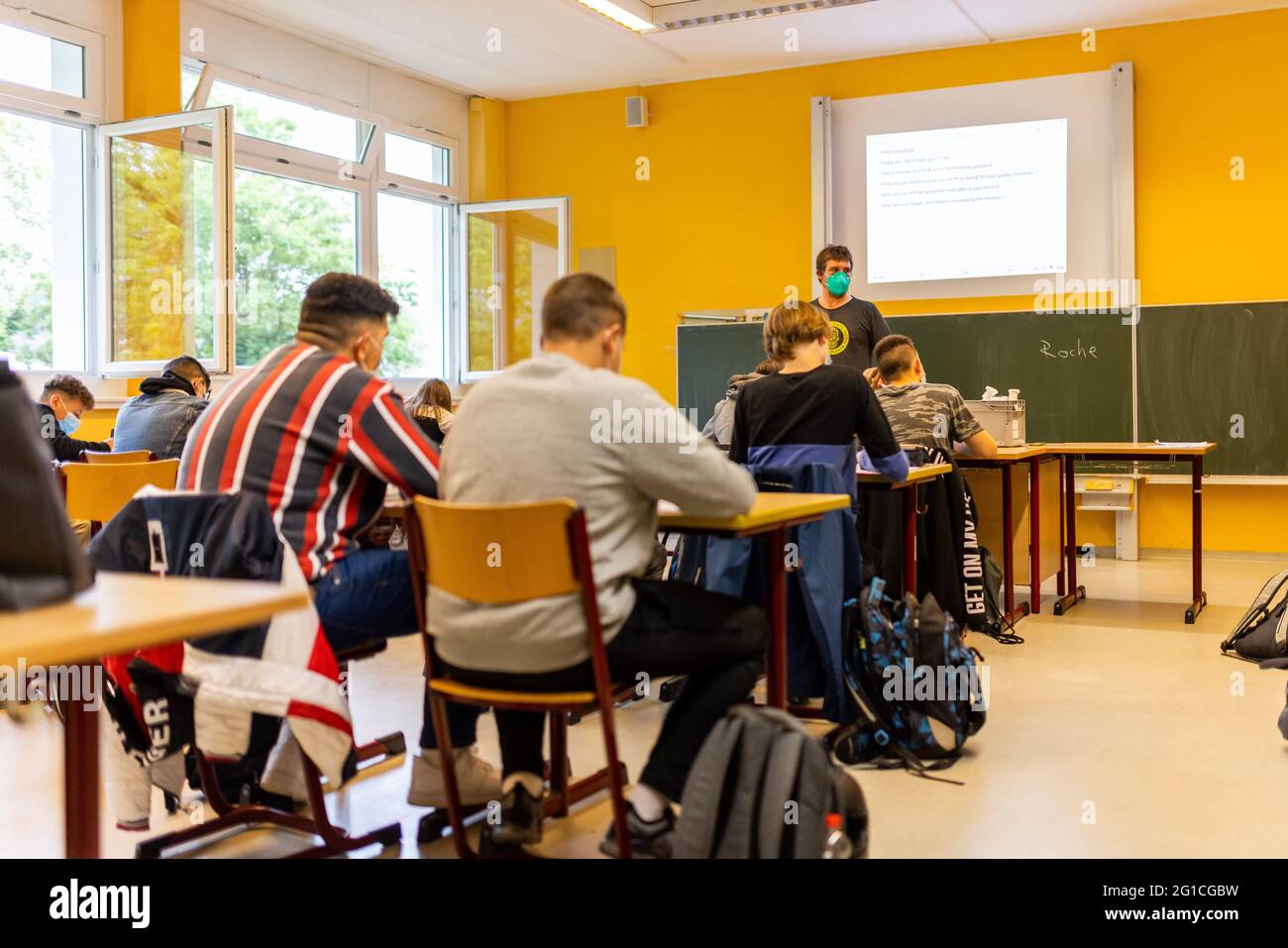 07 giugno 2021, Baden-Wuerttemberg, Heitersheim: Gli studenti si siedono in  classe il lunedì mattina mentre un insegnante si trova di fronte alla  lavagna accanto alle finestre aperte. Sono tutti tornati alla scuola