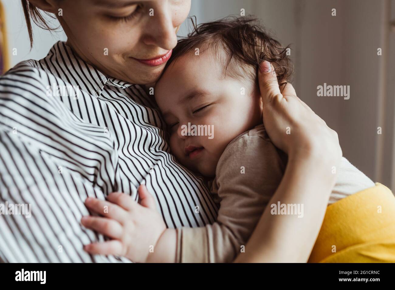 Madre che guarda il bambino maschio addormentato a casa Foto Stock