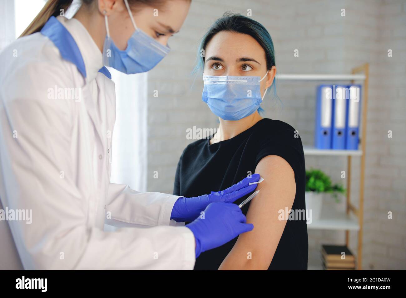 La donna bruna sta guardando il medico mentre viene vaccinata in ospedale Foto Stock