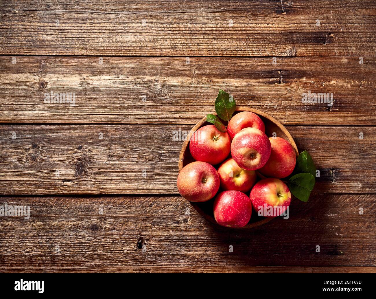 Mele mature su vecchio sfondo di legno con foglie di mela. Foto Stock