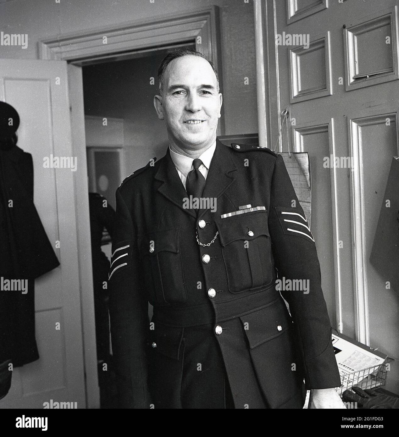 Anni '60, storico, polizia in uniforme Sergente in piedi alla porta della stazione di polizia, Kelty, Fife, Scozia, Regno Unito. Foto Stock