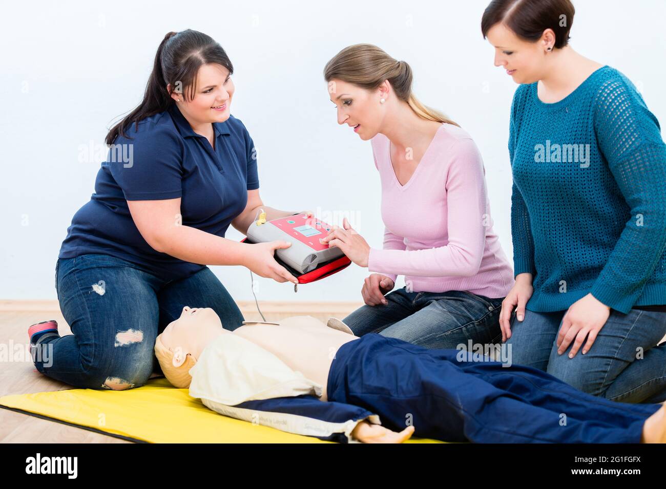 I partecipanti al primo soccorso imparano a utilizzare il defibrillatore per la rianimazione nel corso di primo soccorso Foto Stock