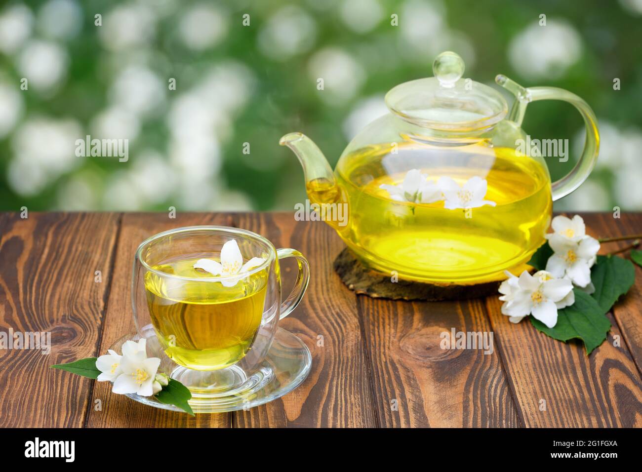 tazza di vetro e teiera di tè verde con fiori di gelsomino Foto Stock