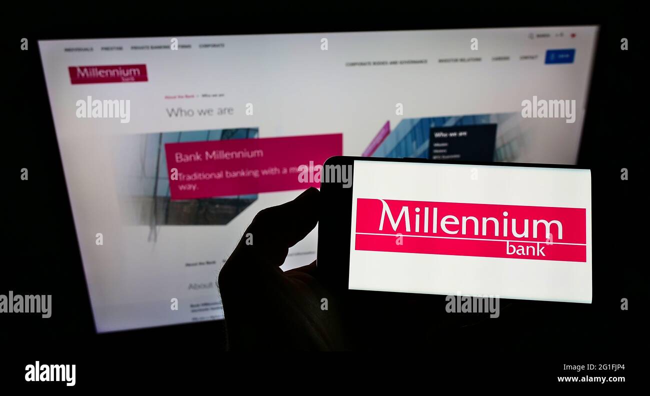 Persona in possesso di smartphone con logo della società finanziaria polacca Bank Millennium S.A. sullo schermo davanti al sito Web. Mettere a fuoco il display del telefono. Foto Stock