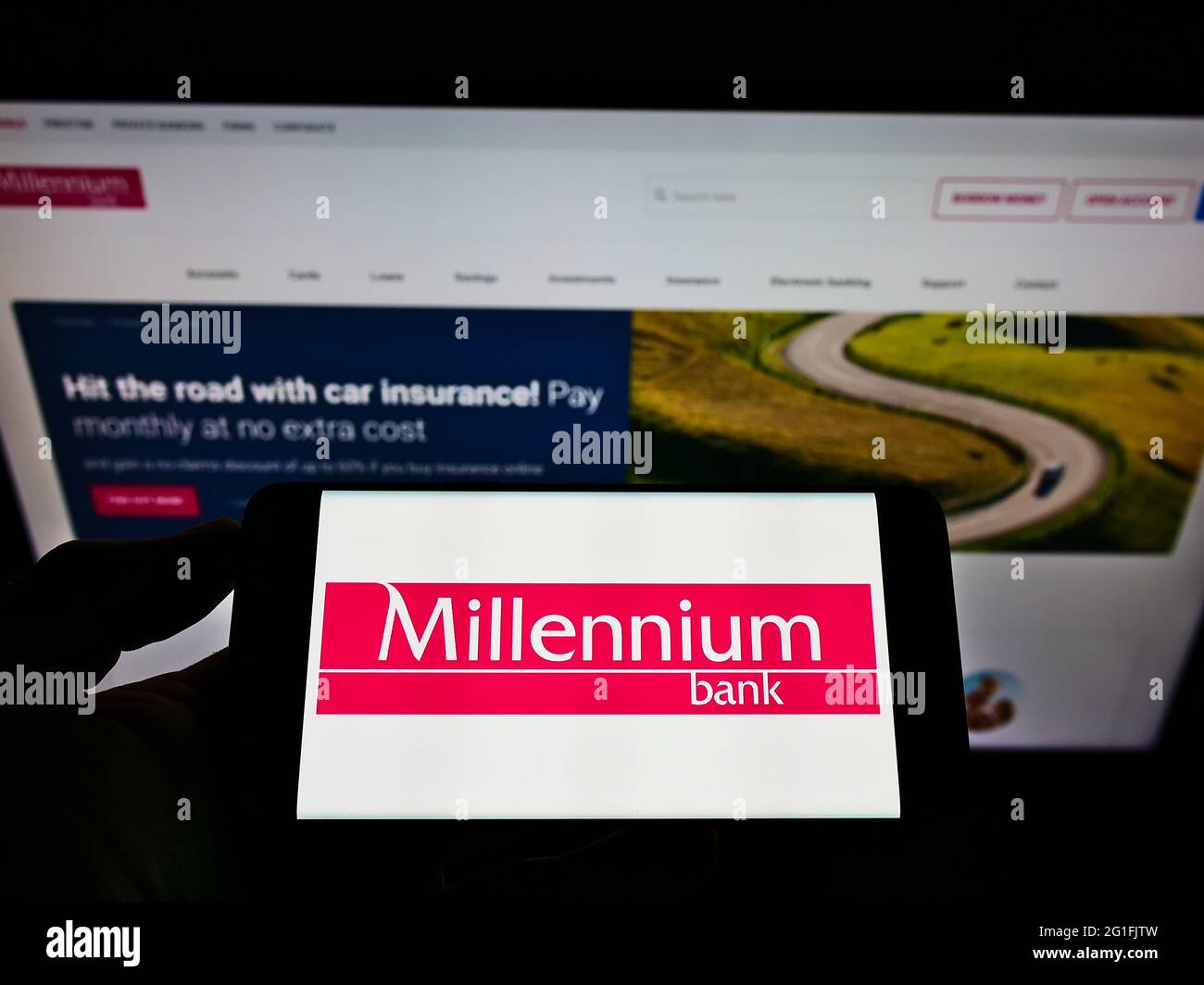 Persona che detiene il cellulare con il logo della società finanziaria polacca Bank Millennium S.A. sullo schermo di fronte al sito web aziendale. Mettere a fuoco il display del telefono. Foto Stock