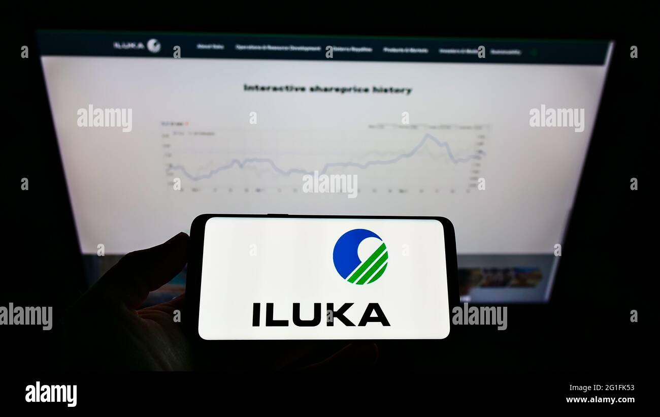Persona che detiene smartphone con il logo della società mineraria australiana Iluka Resources Limited sullo schermo di fronte al sito Web. Mettere a fuoco il display del telefono. Foto Stock