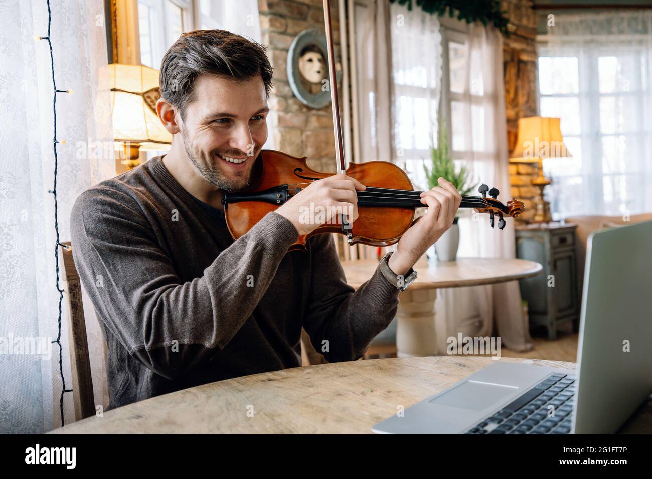 Insegnante di musica maschile insegnando a suonare una canzone il violino  online durante una videochiamata Foto stock - Alamy