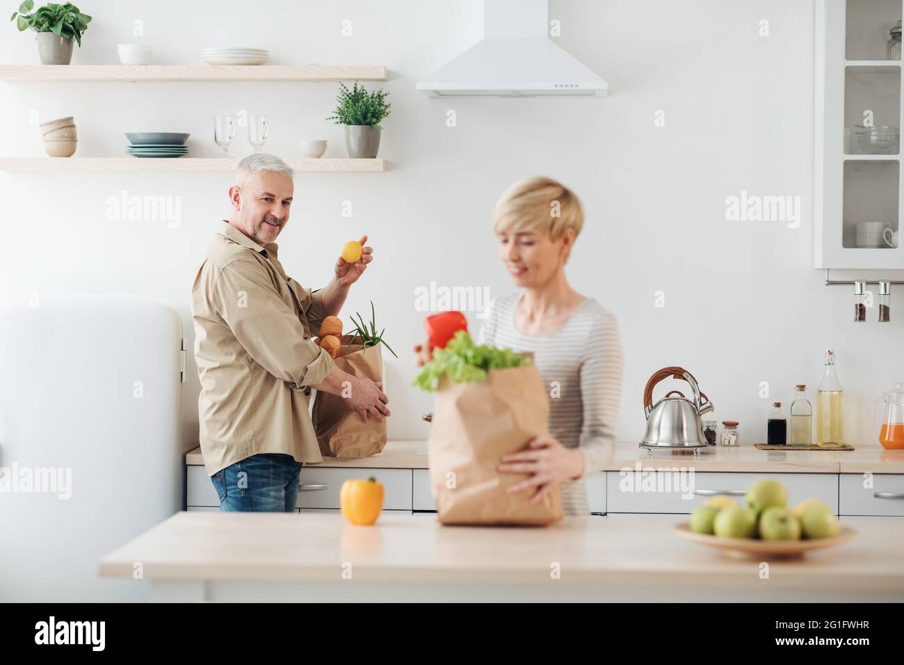 Coppia disimballaggio prodotti freschi dal mercato in cucina, consegna Foto Stock