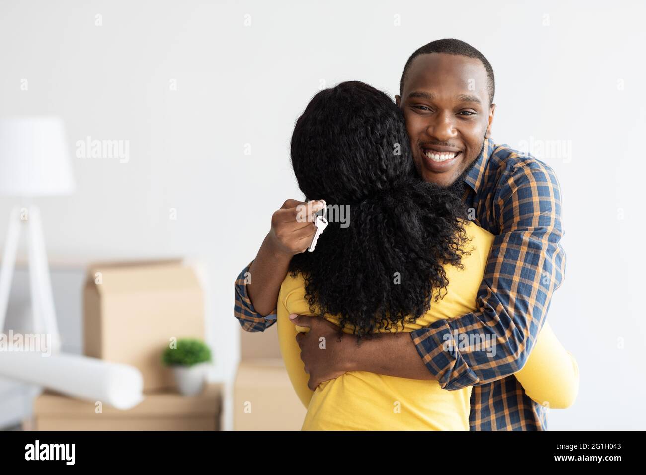 Proprietari di case. Happy African American Man Holding Home Keys e abbracciando la moglie Foto Stock