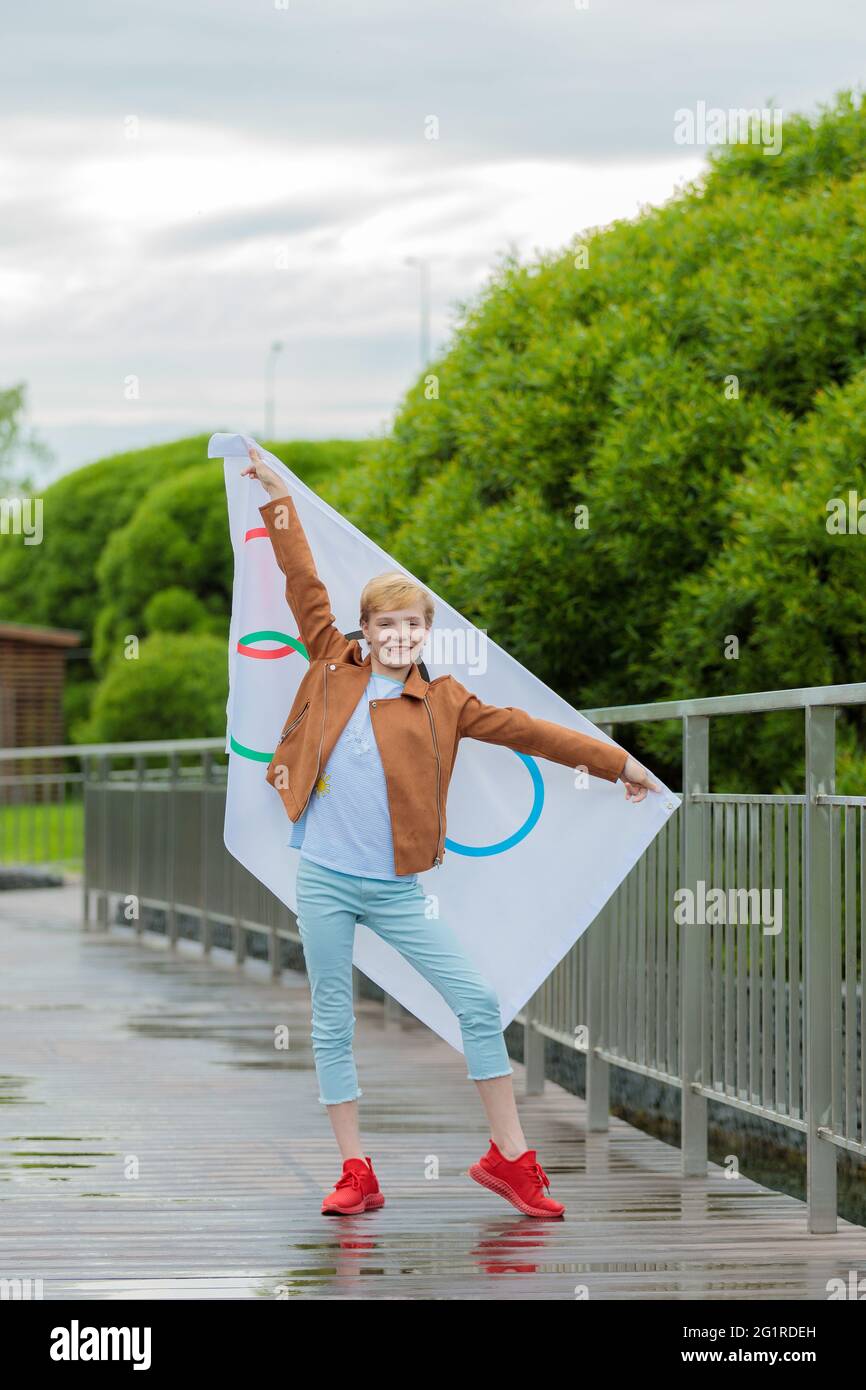 La bionda che sventolava la bandiera olimpica all'aperto nel parco. Giochi Olimpici estivi. Mosca Russia 28 maggio 2021 Foto Stock