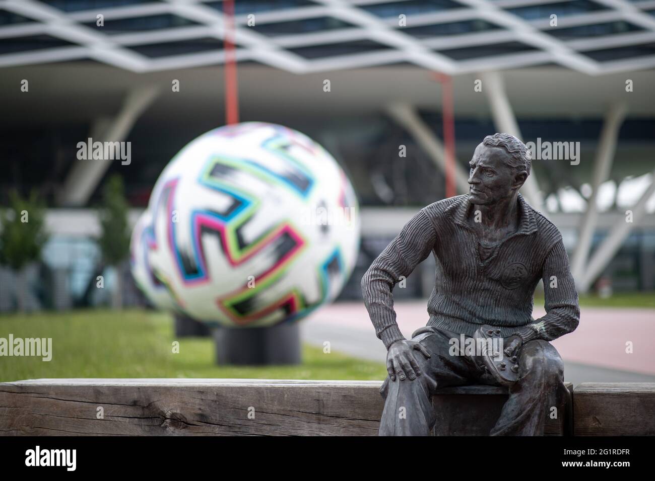 07 giugno 2021, Baviera, Herzogenaurach: Una statua del fondatore Adolf 'Adi' Dassler è stata eretta di fronte all'edificio degli uffici 'Arena' sui terreni di adidas produttori di articoli sportivi. Sullo sfondo c'è un pallone ufficiale oversize 'Uniforia' dell'EURO 2020. La squadra nazionale tedesca di calcio e il personale di supporto soggiorneranno presso il "Home Ground" presso la sede del partner DFB adidas per tutta la durata del Campionato europeo. Foto: Daniel Karmann/dpa Foto Stock
