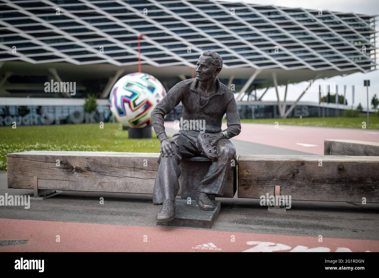 Herzogenaurach, Germania. 07 giugno 2021. Una statua del fondatore Adolf 'Adi' Dassler è stata eretta di fronte all'edificio degli uffici 'Arena' sui terreni di adidas produttori di articoli sportivi. Sullo sfondo c'è un pallone ufficiale oversize 'Uniforia' dell'EURO 2020. La squadra nazionale tedesca di calcio e il personale di supporto soggiorneranno presso il "Home Ground" presso la sede del partner DFB adidas per tutta la durata del Campionato europeo. Credit: Daniel Karmann/dpa/Alamy Live News Foto Stock