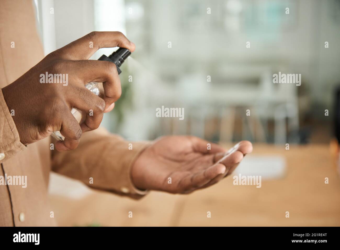 Uomo d'affari africano che usa l'igienizzatore per le mani in un ufficio Foto Stock