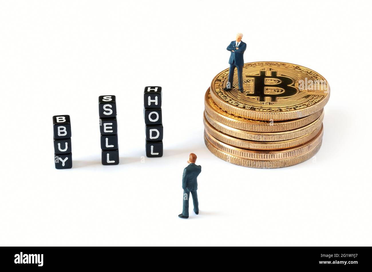 Cubi neri con TESTO SU sfondo bianco ACQUISTA, VENDI e HODL. Un uomo d'affari figurine in piedi su pila di bitcoin mentre l'altro guardando cubetti. Foto Stock