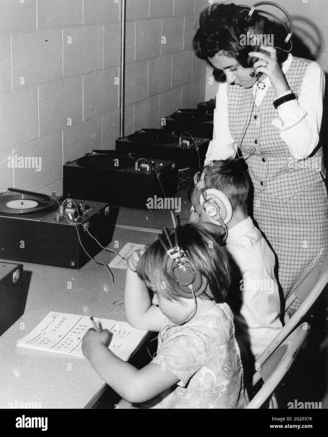 I bambini in una scuola della Pennsylvania seguono le istruzioni registrate mentre fanno le lezioni in aritmetica mentre un insegnante guarda sopra. Le registrazioni fanno parte di un metodo di insegnamento sperimentale chiamato Instructions Instructions Instructions Instructions (IPI), che permette ad ogni allievo di progredire al proprio ritmo, PA, 1970. (Foto di United States Information Agency/RBM Vintage Images) Foto Stock